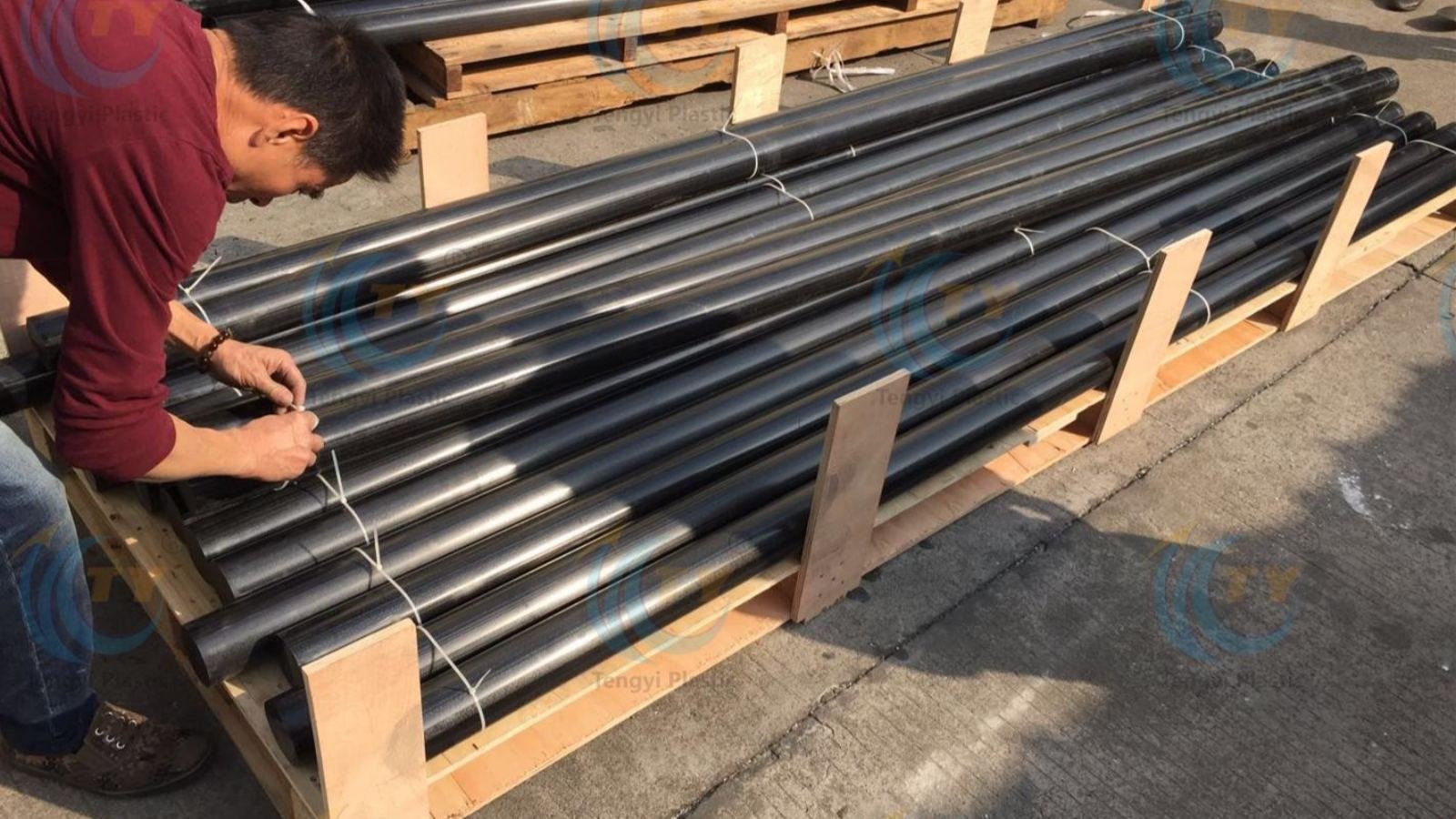 3-meter black POM rods strapped on custom wooden pallet with nylon tape