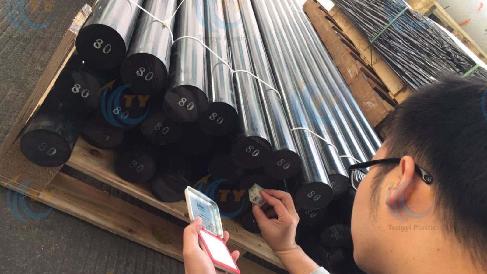 Black POM rods on wooden pallet with visible diameter labels