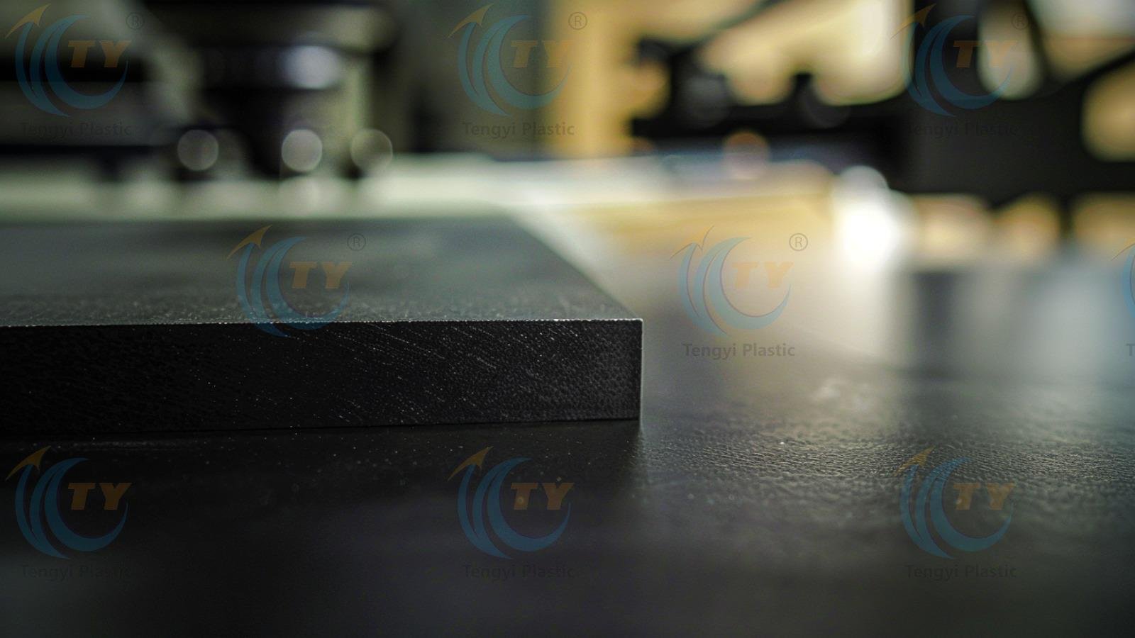 Black POM sheet on workbench with CNC machines in the background