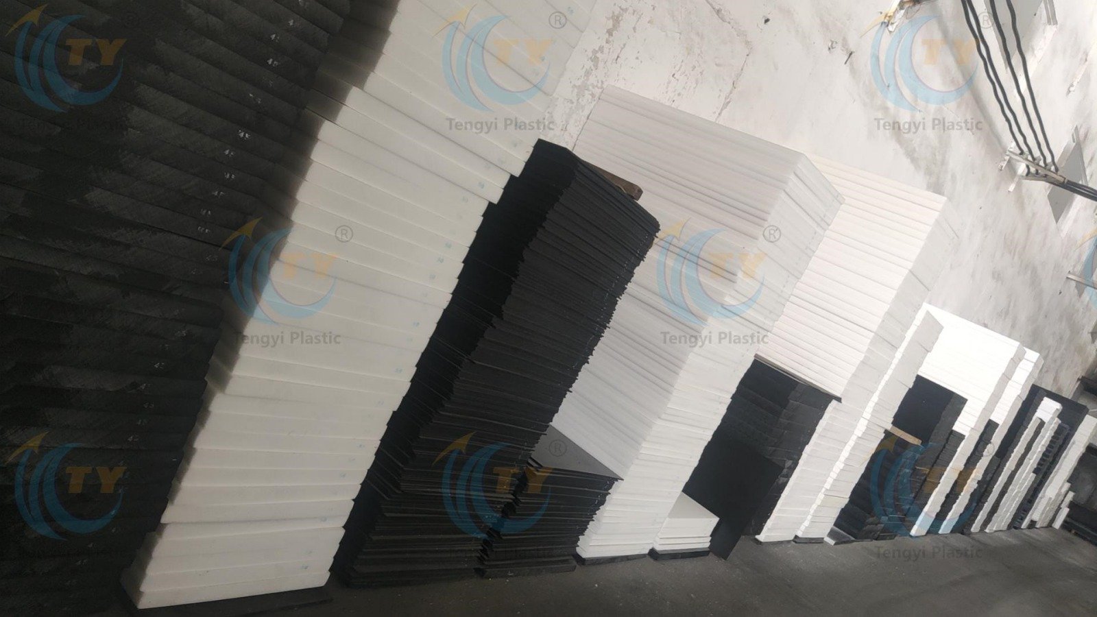 Stacked black and white POM sheets of different sizes and thicknesses in warehouse
